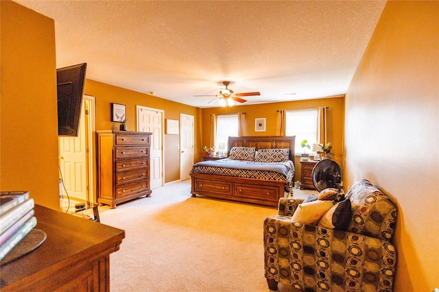 bedroom with a ceiling fan, light colored carpet, and a textured ceiling