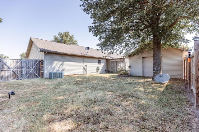 rear view of house with central air condition unit, a lawn, a shingled roof, and fence