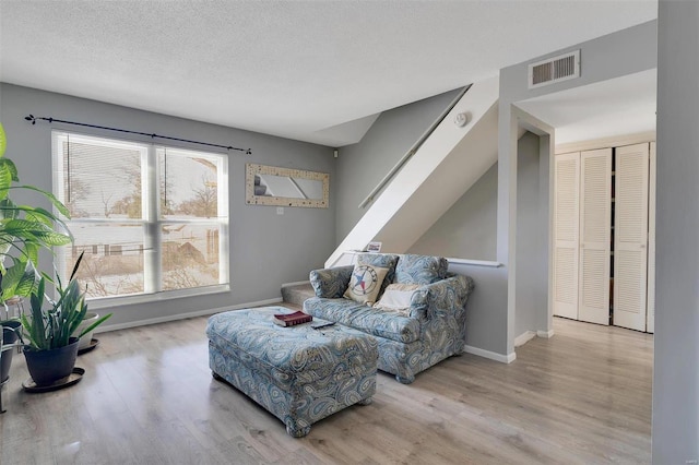 living room with a wealth of natural light, light hardwood / wood-style flooring, and a textured ceiling