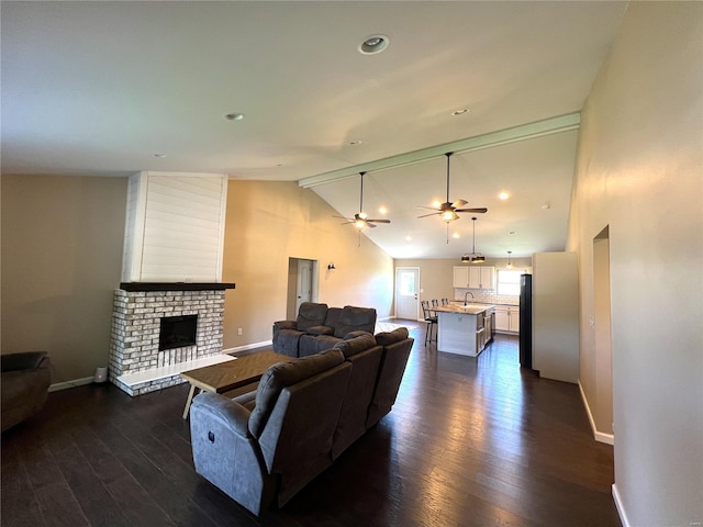 living room with sink, high vaulted ceiling, dark wood-type flooring, ceiling fan, and a brick fireplace