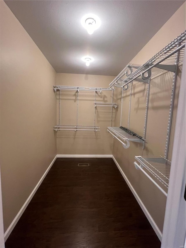 walk in closet with dark hardwood / wood-style flooring