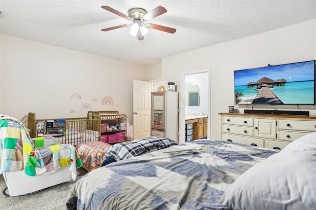 carpeted bedroom featuring ensuite bathroom, ceiling fan, and a textured ceiling