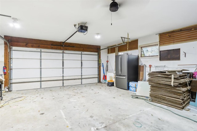 garage featuring a garage door opener and stainless steel refrigerator