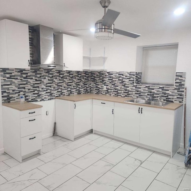 kitchen featuring backsplash, wall chimney exhaust hood, white cabinetry, and sink