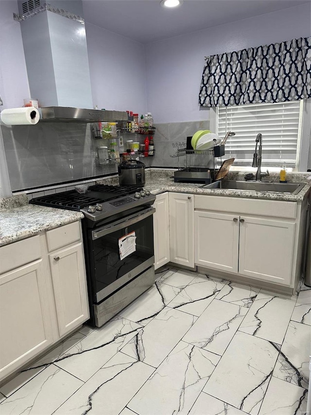 kitchen with island exhaust hood, backsplash, stainless steel range with gas stovetop, light tile patterned floors, and sink