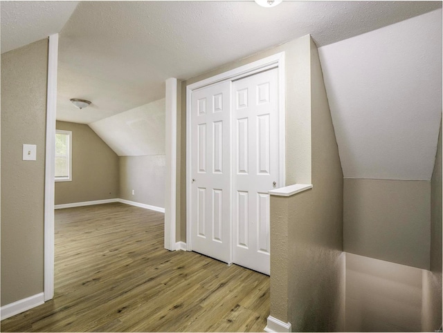 bonus room featuring lofted ceiling, hardwood / wood-style flooring, and a textured ceiling