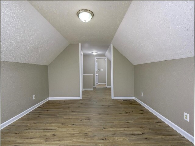 additional living space with lofted ceiling, hardwood / wood-style flooring, and a textured ceiling