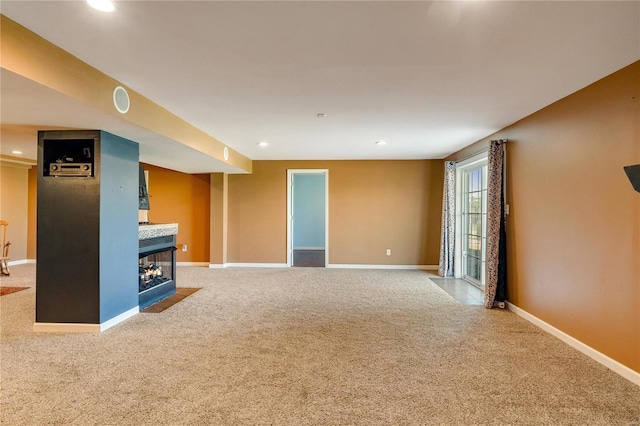 unfurnished living room featuring a multi sided fireplace and carpet