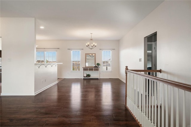 unfurnished room featuring an inviting chandelier and dark hardwood / wood-style floors