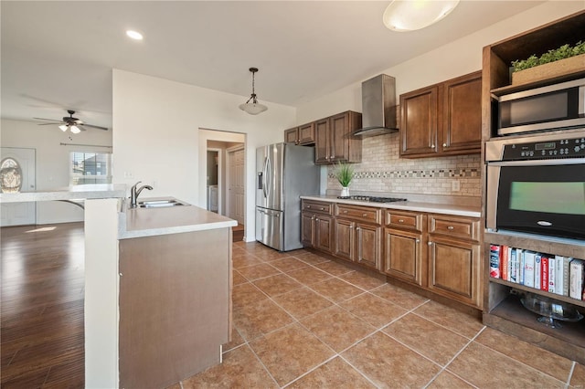 kitchen featuring appliances with stainless steel finishes, sink, dark tile patterned floors, wall chimney exhaust hood, and decorative light fixtures