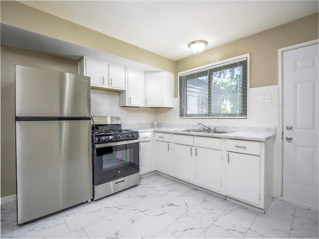 kitchen featuring tasteful backsplash, white cabinets, appliances with stainless steel finishes, and sink