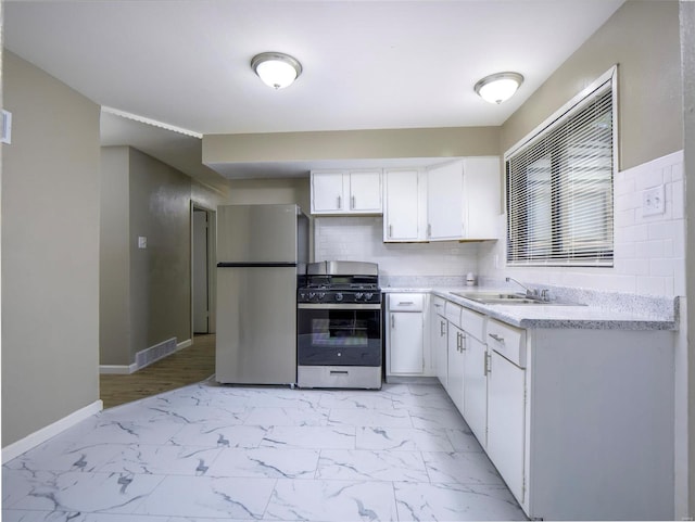 kitchen with appliances with stainless steel finishes, decorative backsplash, white cabinetry, and sink