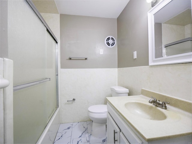 full bathroom with enclosed tub / shower combo, vanity, and toilet