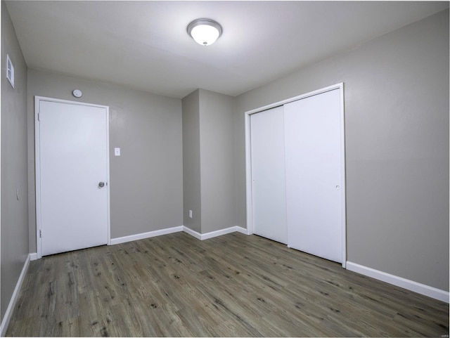 unfurnished bedroom featuring a closet and dark hardwood / wood-style flooring