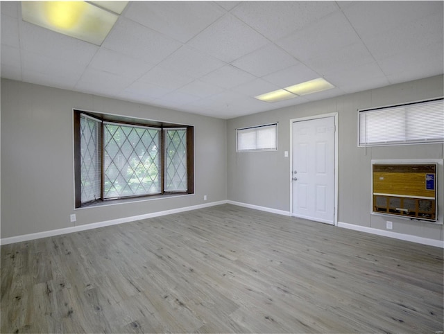 unfurnished room with a drop ceiling and hardwood / wood-style floors