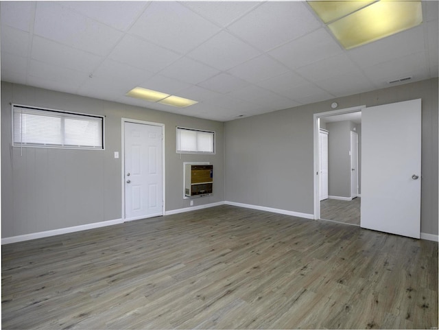 basement featuring hardwood / wood-style flooring, a paneled ceiling, and heating unit