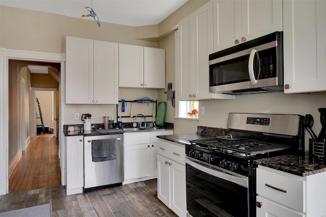 kitchen featuring dark wood-type flooring, appliances with stainless steel finishes, white cabinetry, and sink