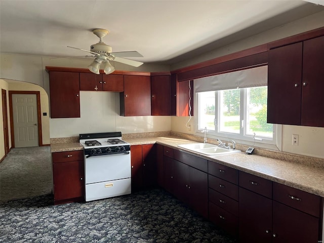 kitchen with dark carpet, white gas stove, sink, and ceiling fan