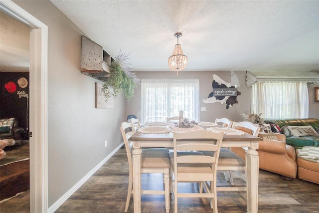 dining space with a textured ceiling, a notable chandelier, and dark wood-type flooring