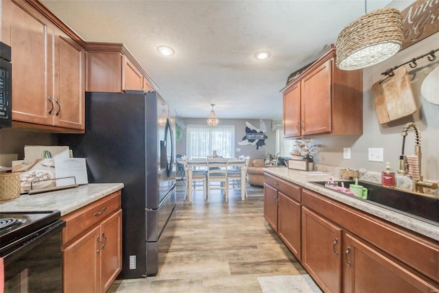 kitchen with black appliances, light hardwood / wood-style floors, sink, and hanging light fixtures