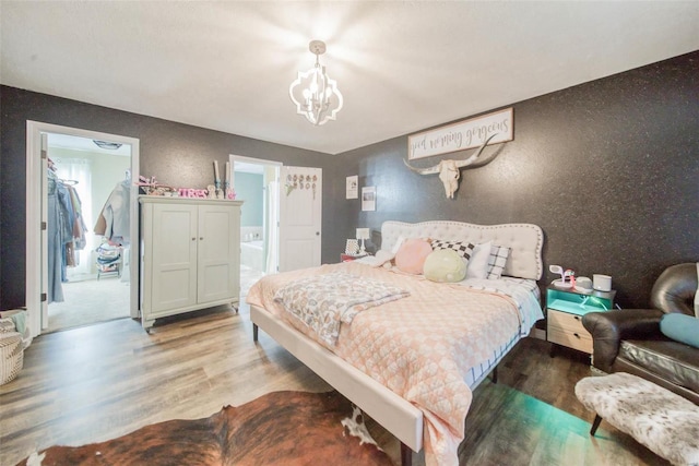 bedroom featuring a notable chandelier, light hardwood / wood-style floors, and connected bathroom