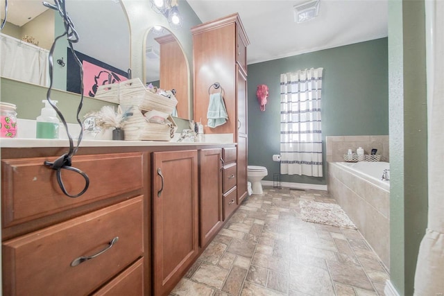 bathroom featuring tiled tub, vanity, and toilet