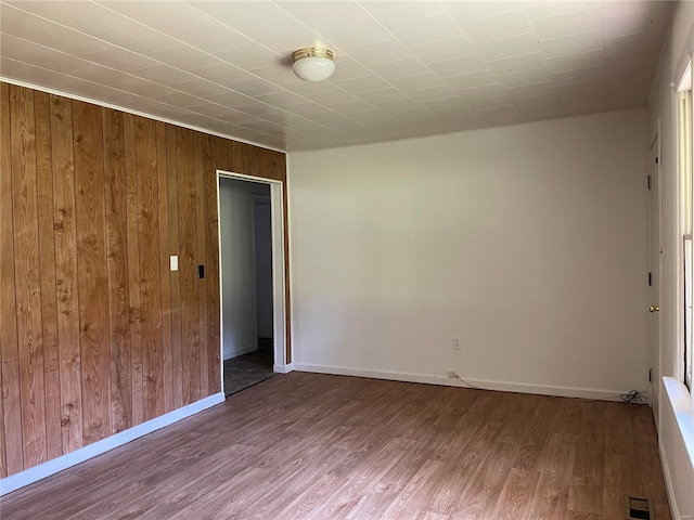 unfurnished room with hardwood / wood-style floors and wooden walls