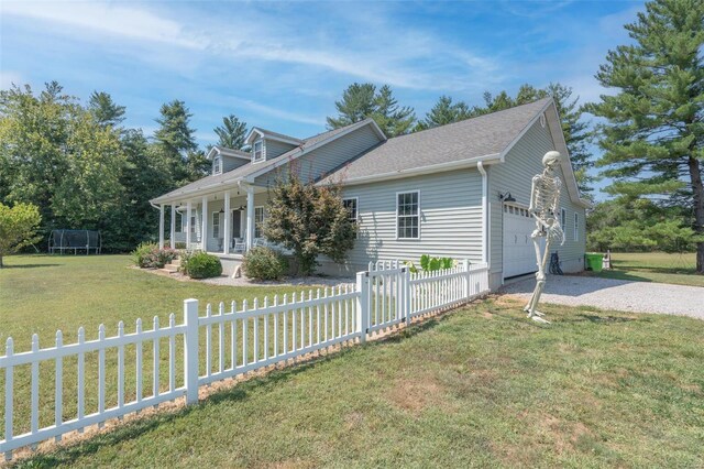 view of property exterior with a trampoline, a fenced front yard, a lawn, a garage, and driveway