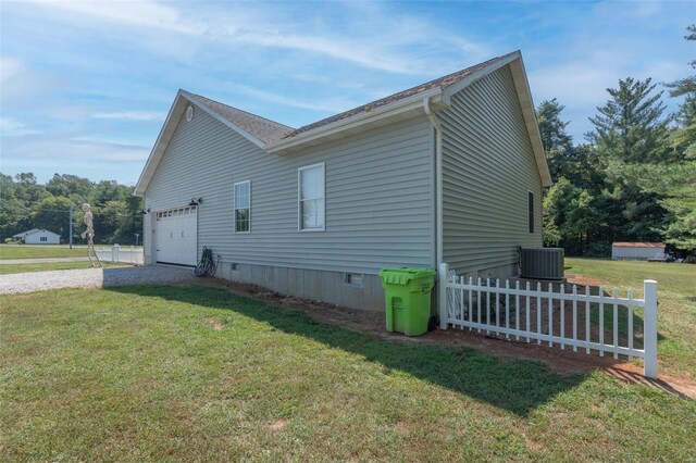 view of side of home with fence, driveway, a garage, crawl space, and a lawn