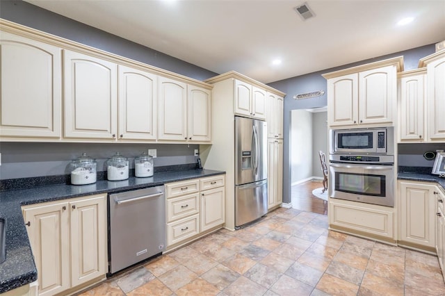 kitchen featuring stainless steel appliances, baseboards, cream cabinets, and visible vents