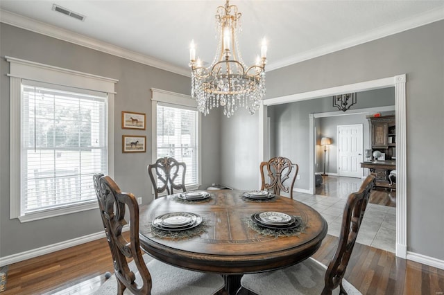 dining room featuring an inviting chandelier, crown molding, wood finished floors, and visible vents