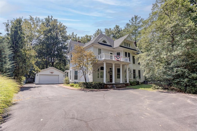 victorian home with a garage, a porch, and an outbuilding