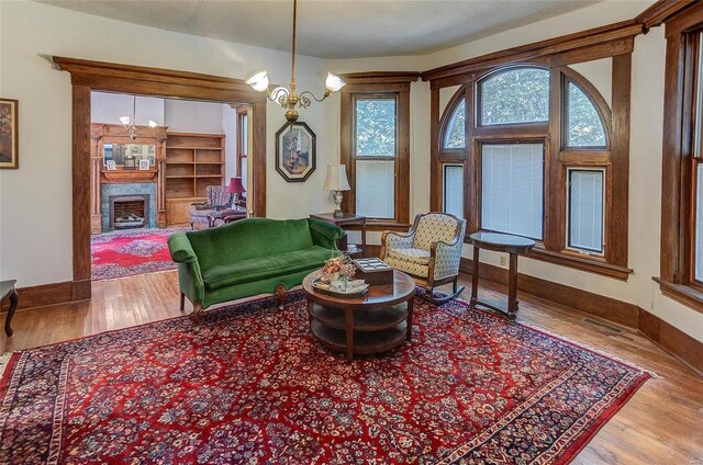 living room with light wood-type flooring, a fireplace, and a notable chandelier