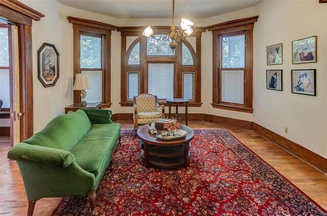 sitting room featuring a notable chandelier, wood-type flooring, and a healthy amount of sunlight