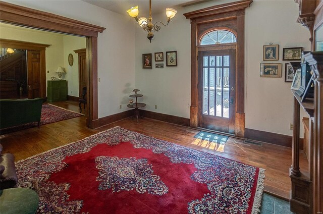 foyer entrance with hardwood / wood-style floors, a notable chandelier, and a healthy amount of sunlight