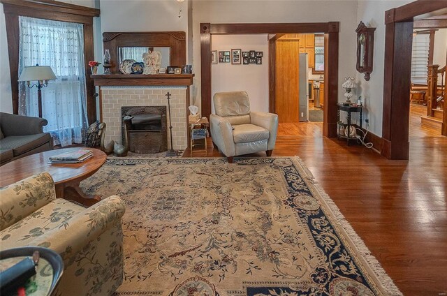 living room with hardwood / wood-style floors and a brick fireplace