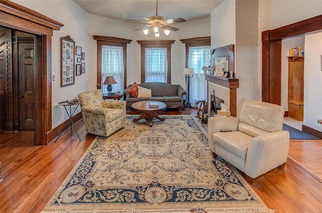 living room featuring a wealth of natural light, a brick fireplace, ceiling fan, and light hardwood / wood-style floors