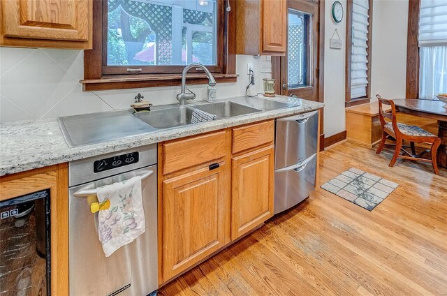 kitchen featuring backsplash, dishwasher, light hardwood / wood-style flooring, sink, and stainless steel dishwasher