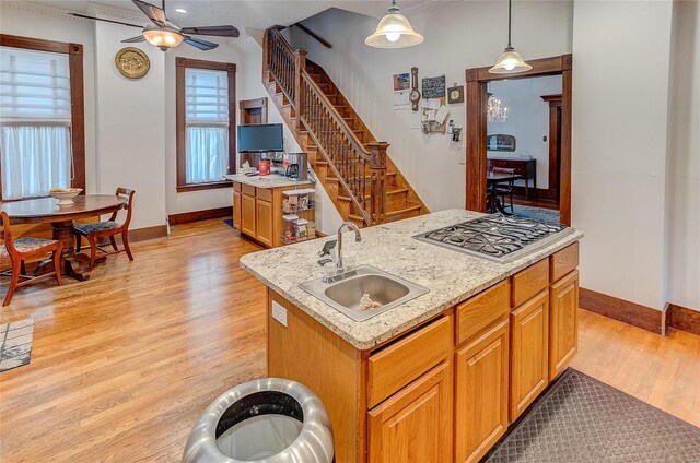 kitchen with a kitchen island with sink, pendant lighting, light hardwood / wood-style flooring, sink, and ceiling fan