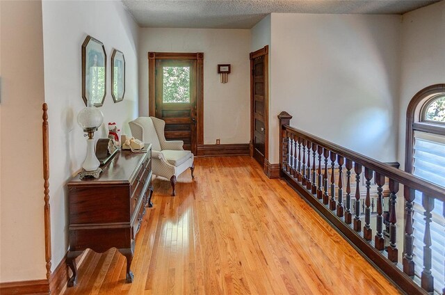 hallway featuring light wood-type flooring and a textured ceiling