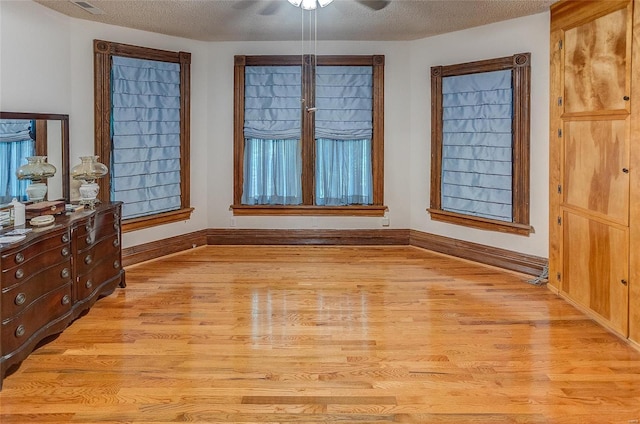 unfurnished bedroom featuring a textured ceiling, ceiling fan, and light wood-type flooring