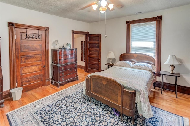 bedroom with hardwood / wood-style floors, ceiling fan, and a textured ceiling