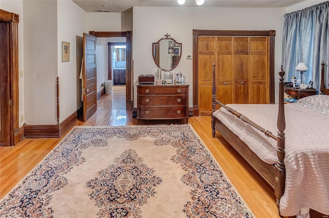 bedroom featuring a textured ceiling and light hardwood / wood-style floors