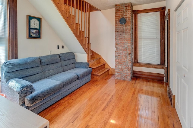 living room featuring brick wall, light hardwood / wood-style flooring, and a textured ceiling