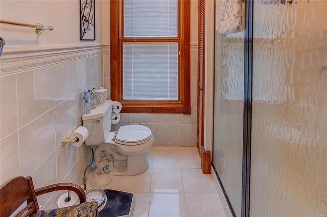 bathroom with tile walls, a shower with shower door, toilet, and tile patterned floors