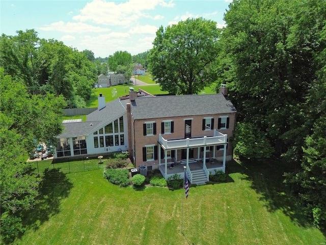 rear view of property featuring central AC unit, a sunroom, and a lawn