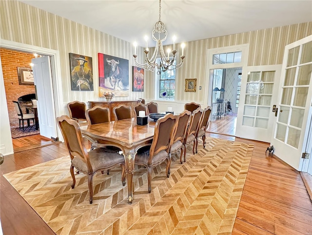 dining space with french doors, light hardwood / wood-style flooring, and a chandelier