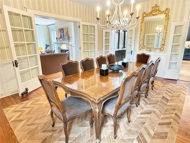 dining area with light hardwood / wood-style flooring, french doors, and a chandelier