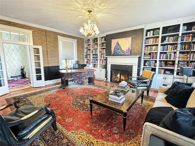 living room with ornamental molding, an inviting chandelier, hardwood / wood-style flooring, and built in shelves