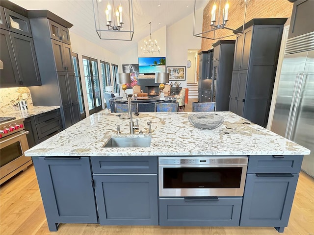 kitchen featuring high end appliances, vaulted ceiling, decorative light fixtures, backsplash, and a chandelier